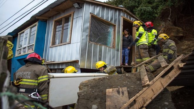 aolo ÁvilaUnos bomberos ayudan a retirar este 26 de diciembre los escombros de unas casas destrozadas en Chiloé