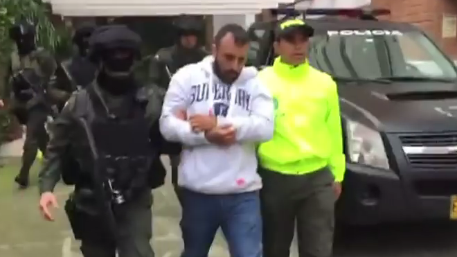 Policía colombiana deteniendo a Camilo un narco que se ayuda con brujería a su salida de un apartamento.