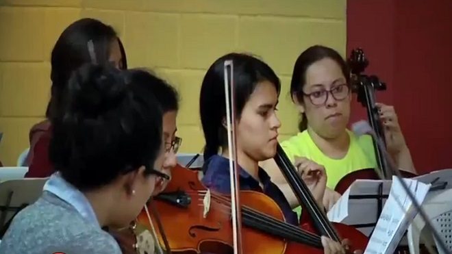 Integrantes de la orquesta sinfónica tocan instrumentos durante ensayo.