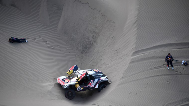 Peugeot's co-driver Daniel Elena (L), from Monaco, gestures on the ground after getting injured when he and French driver Sebastien Loeb (R) ran into sand trouble during the 2018 Dakar Rally Stage 5 between San Juan De Marcona and Arequipa in Peru, on January 10, 2018. Sebastien Loeb was forced to pull out of the Dakar Rally after a back injury suffered by his co-driver in a disastrous fifth stage won by defending champion Stephane Peterhansel. Franck FIFE / AFP