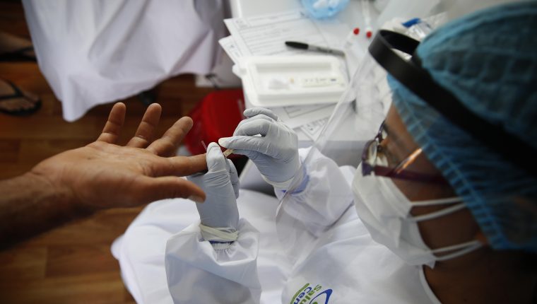 AME152. CALI (COLOMBIA), 15/05/2020.- Una funcionaria le toma una muestra de sangre a un hombre para una prueba rápida para COVID-19 este viernes, en una plaza de mercado de Cali (Colombia). Funcionarios de la secretaría de salud de la ciudad buscan entre vendedores y comerciantes del mercado, posibles casos positivos por el alto flujo de personas que trabajan en este lugar. El departamento del Valle del Cauca, cuya capital es la ciudad de Cali, es el segundo más afectado por la pandemia en Colombia, que supera los 13.000 casos. EFE/ Ernesto Guzmán Jr